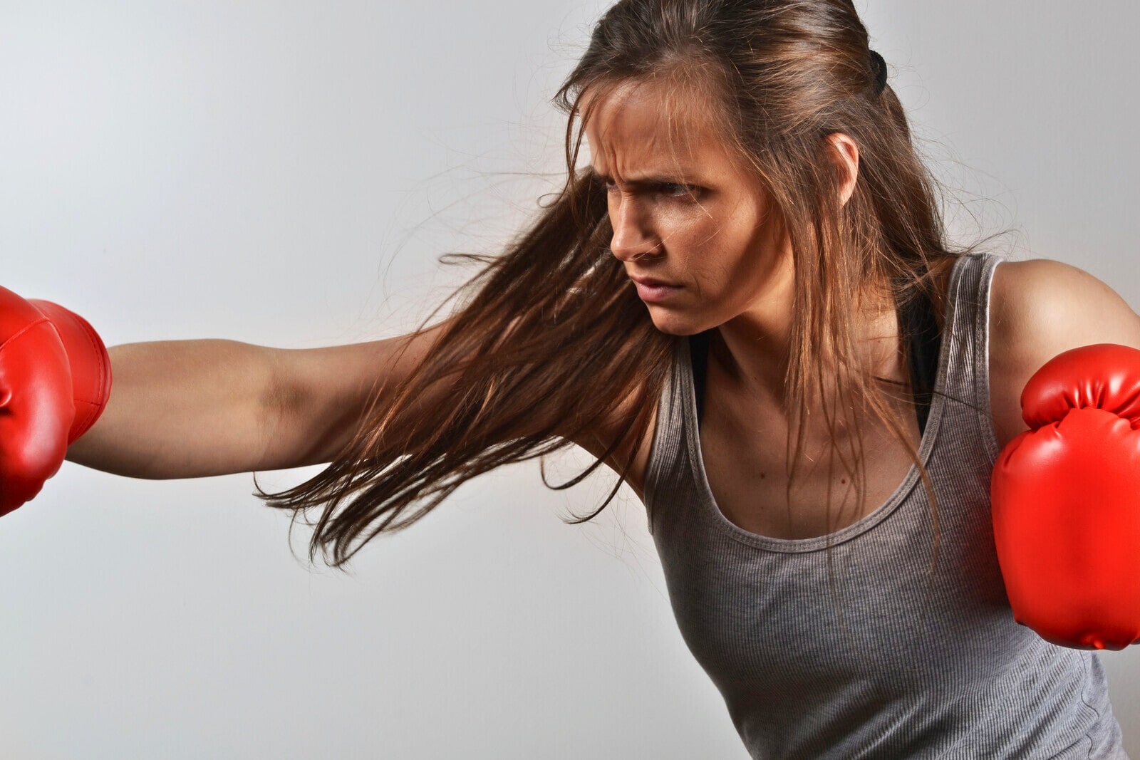 woman with boxing gloves on hitting something out of shot