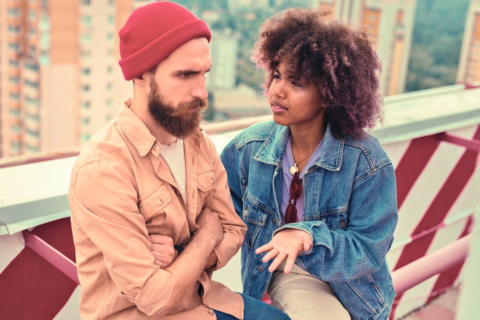 young woman wanting to make a compromise but her boyfriend has his arms crossed in defiance