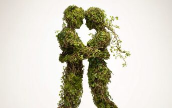 Two human figures made of intertwined vines, leaves, and moss stand face to face, holding each other closely as if about to kiss, against a plain white background.