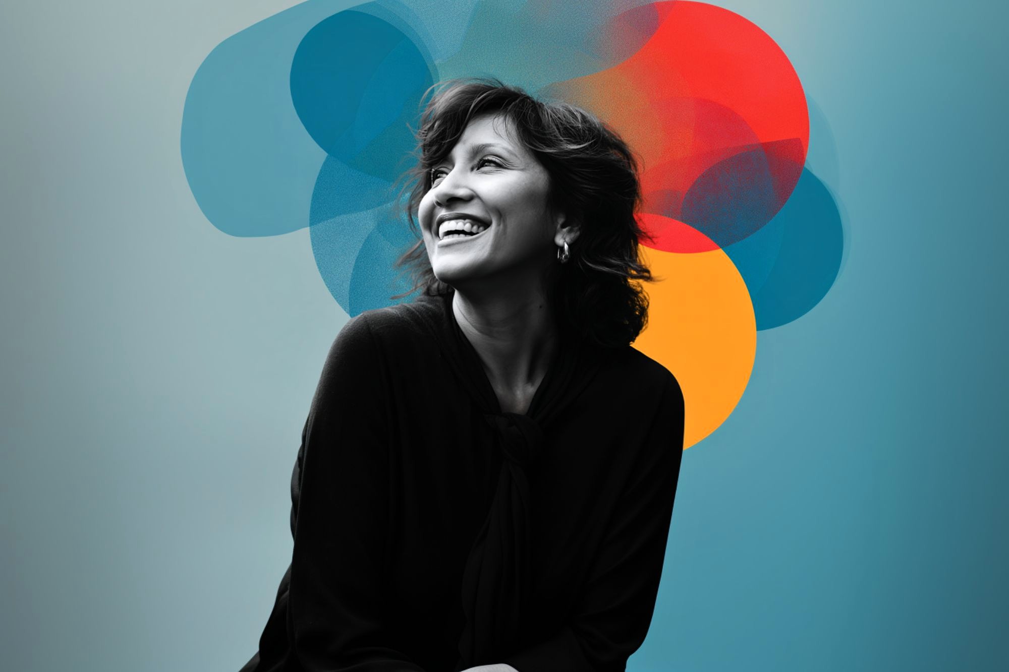 A smiling woman sits against a blue background with overlapping, translucent circles in blue, red, and yellow behind her head, creating an artistic and vibrant effect.